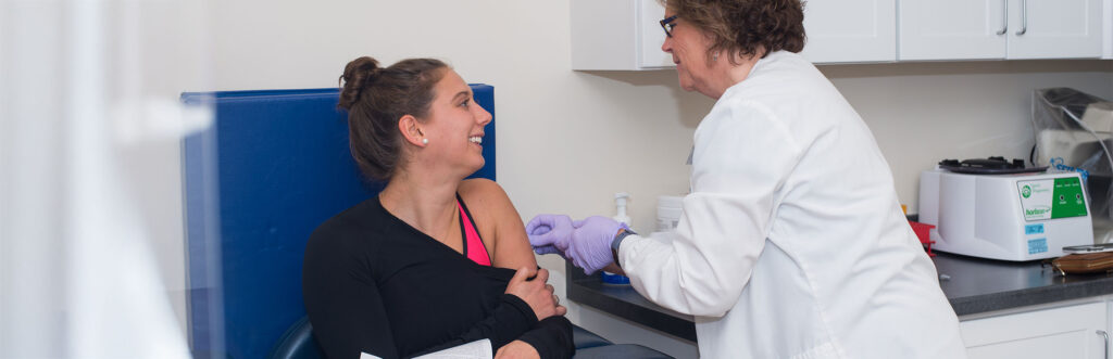 A U N E healthcare professional gives a student a vaccine via a shot in their upper arm