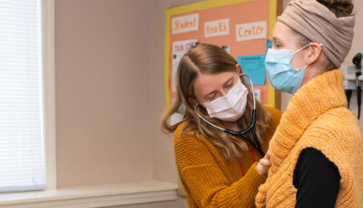 A Student Health Services doctor uses a stethoscope to listen to a student's heartbeat