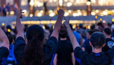 Students cheering in front of a light-up building at night