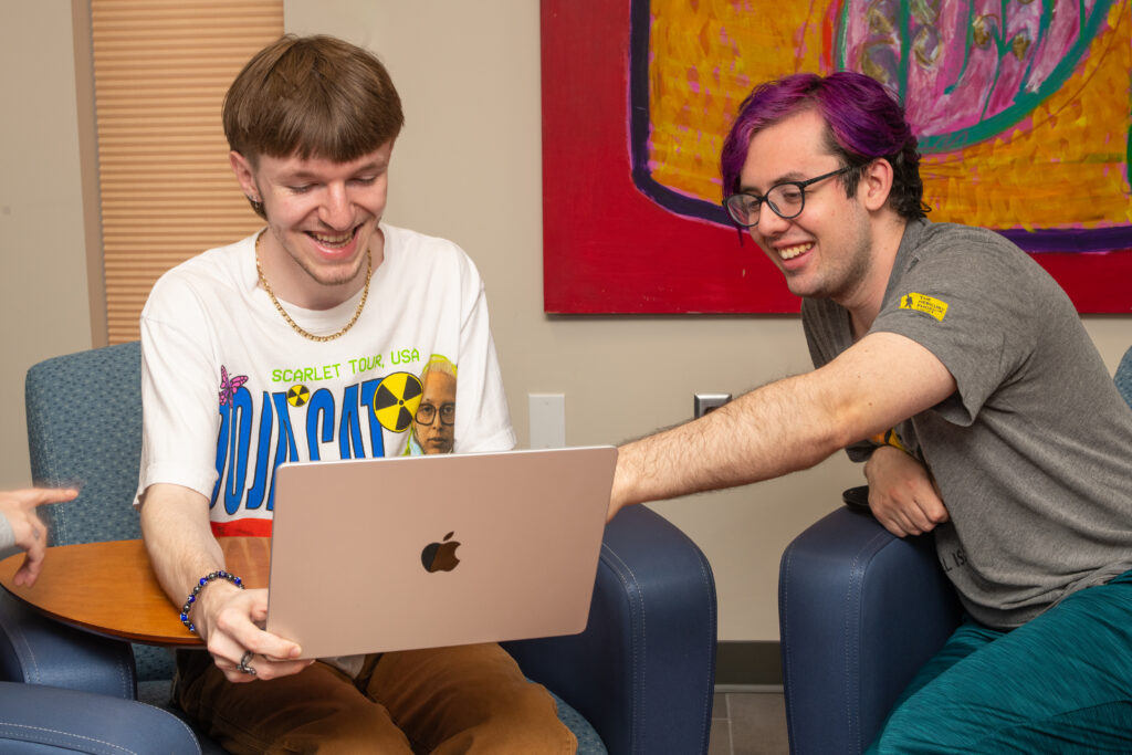 A student assists another student as they sit together in the library