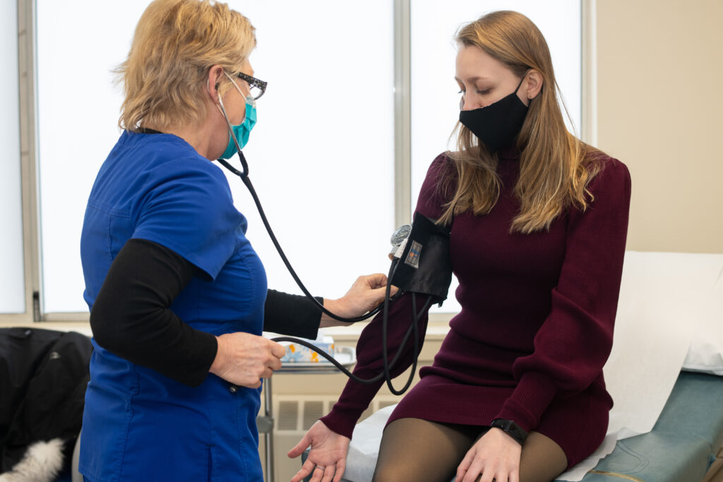 A health services nurse checks the blood pressure of a student