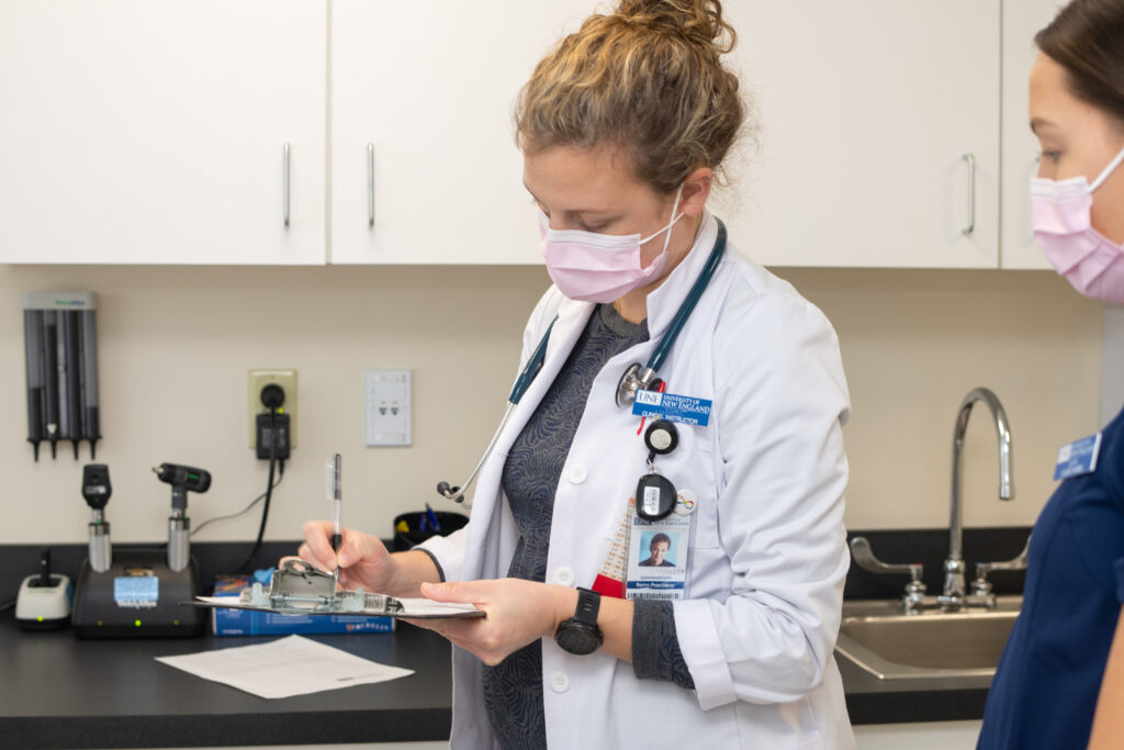 A U N E doctor takes notes in a patient's room