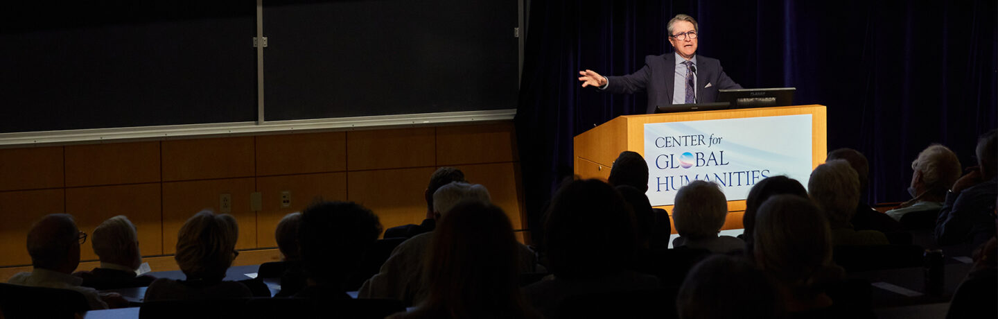 A presenter speaks to a crowd from a podium during a Center for Global Humanities lecture