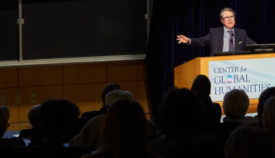 A presenter speaks to a crowd from a podium during a Center for Global Humanities lecture